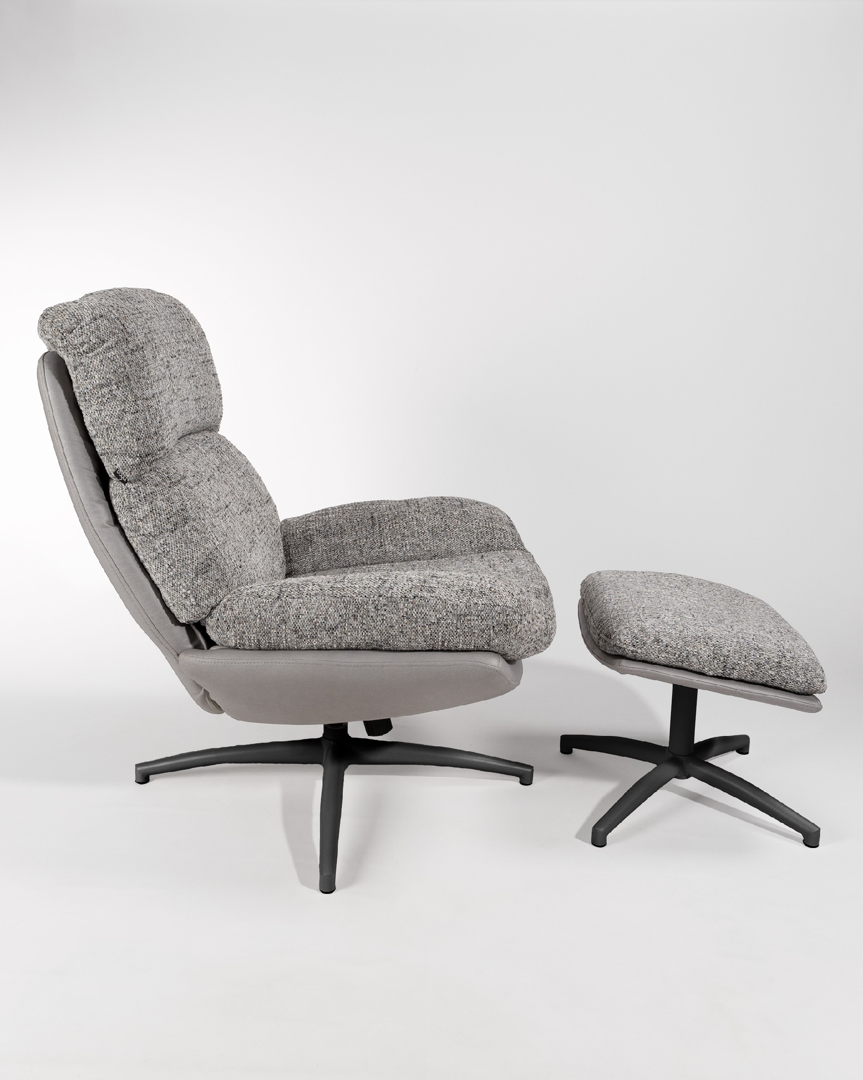 Fauteuil Denia avec rembourrage gris et tempête avec pouf en structure métallique noire, basculant et tournant à 360°.