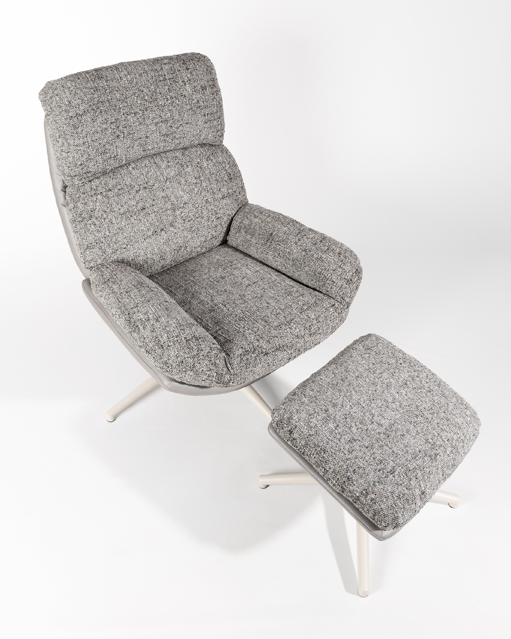 Fauteuil Fresia avec un revêtement gris et tempête avec un pouf à structure métallique ivoire, basculant et rotatif à 360°.